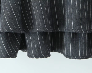 Detailed macro view of dark grey pinstripe fabric and layered ruffle hem stitching