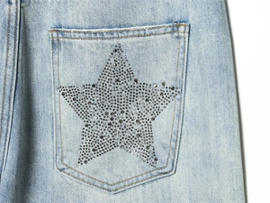 Detail shot of a large silver rhinestone star pattern on the back pocket of light blue jeans