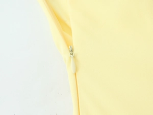 Detail van de onzichtbare ritssluiting en gladde textuur van deze gele Franse jurk