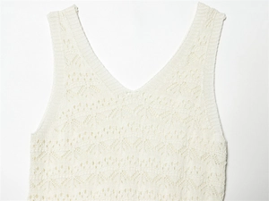 Detail shot of white V-neck sleeveless knit dress featuring intricate crochet patterns