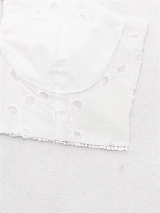 Detailed view of white eyelet embroidery and intricate lace hem on the corset top