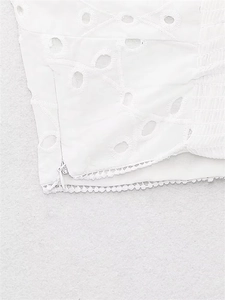 Detail of white cotton eyelet embroidery with smocking and side invisible zipper