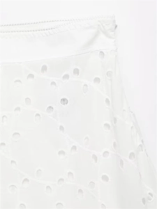 Close-up of white Broderie Anglaise embroidery and delicate eyelet details on the skirt