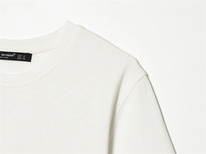Detail eines weißen Baumwoll-T-Shirts mit gewebtem Markenlabel und Größenangaben