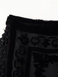 Macro detail of black velvet fabric with floral patterns and handmade tassel lace trim