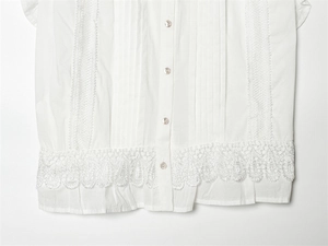 Close-up of white cotton blouse with delicate lace stitching and pearlescent buttons
