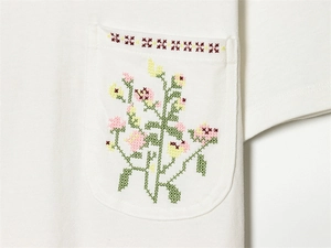 Detailaufnahme der Blumen-Kreuzstich-Stickerei auf weißer Baumwoll-T-Shirt-Tasche