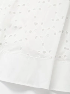 Detailed view of white cotton fabric featuring intricate floral Broderie Anglaise embroidery