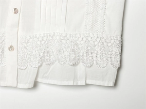 Close-up of white cotton blouse hem featuring delicate lace trim and pearl buttons