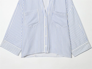 Detail of the blue and white vertical stripe shirt with front pockets and white buttons