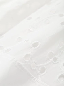 Close-up of white broderie anglaise embroidery on high-quality summer skirt fabric
