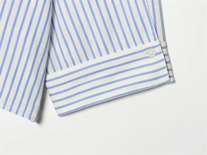 Detail of blue and white striped shirt cuff with white button and fine fabric texture