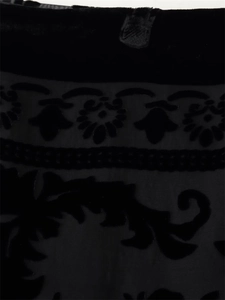 Detailed close-up of premium black velvet fabric with baroque floral flocking patterns