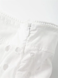 Detailed view of white broderie anglaise fabric with floral embroidery and invisible zipper