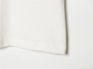 Detail der flachen Doppelnadel-Nähte am Saum eines weißen Baumwollstrick-T-Shirts