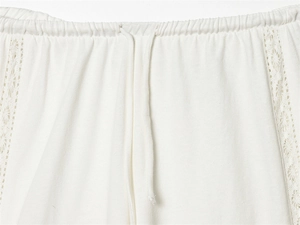 Detail der weißen Baumwollhose mit Kordelzug am Bund und floraler Stickerei-Spitze
