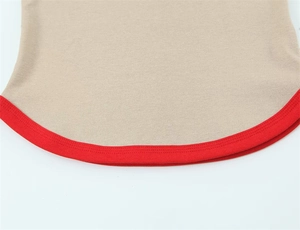 Detail of beige knit top hem featuring a distinctive red contrast piped trim and smooth texture