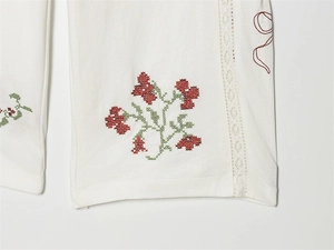 Detailansicht weißer Baumwollhose mit Blumen-Kreuzstich und Spitzenstickerei-Besatz