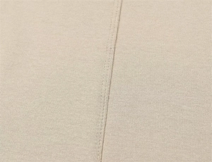 Detail shot of beige knit fabric texture with durable reinforced double stitching