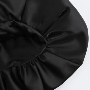 Detail von schwarzer Satin-Schlafmütze mit elastischem Rand und seidiger Textur