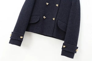 Détail d'un manteau en laine bleu marine avec boutons dorés bombés et poches à rabat