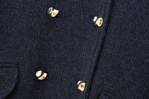 Détail des boutons dorés artistiques sur une veste en laine mélangée bleu marine