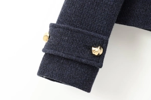 Détail de la manche d'une veste en tweed bleu marine avec boutons dorés en métal