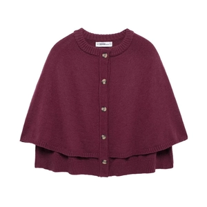 Gros plan d'un poncho en tricot bordeaux avec boutons sur le devant et détails de texture