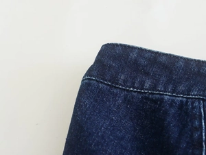 Detalle de la textura de mezclilla azul oscuro y costuras limpias en la cintura