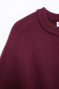 Vue détaillée du pull en maille rouge foncé avec col rond côtelé et texture douce