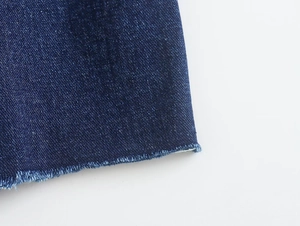 Primer plano de tela vaquera azul oscuro con bordes deshilachados y textura de sarga