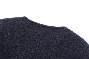 Détail de l'encolure ronde et de la texture en maille gris foncé de la veste mélangée