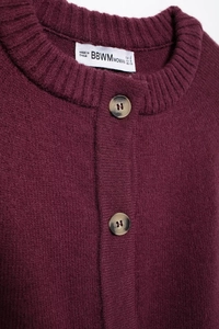 Détail du châle en tricot bordeaux montrant les boutons marbrés et le col rond