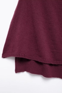 Détail du châle en maille bordeaux avec ourlet côtelé et coupe asymétrique courte