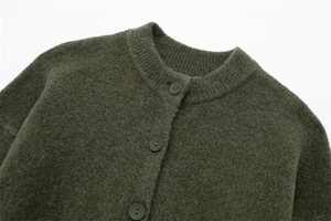 Detail of dark green knitted cardigan showing wool texture and matching buttons