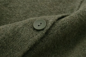 Detailed macro view of olive green wool knit cardigan with textured fabric and round buttons