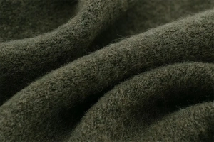 Macro detail of dark olive green knit cardigan fabric with premium fuzzy texture