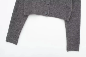 Detail of dark grey knit cardigan showing soft texture, ribbed hem and resin buttons