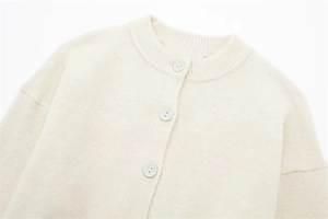 Close-up of ribbed crewneck and button detail on beige knit cardigan sweater