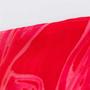Detail shot of sheer red floral chiffon fabric with fine stitching and abstract print
