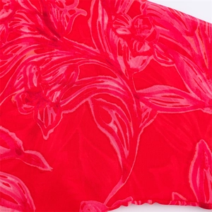 Close-up detail of sheer red floral print chiffon fabric with delicate overlock edge stitching