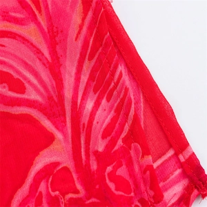 Detailed close-up showing stitching and floral print on red chiffon fabric material