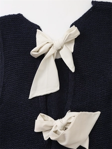 Dettaglio del retro del gilet in maglia blu navy con eleganti fiocchi color crema