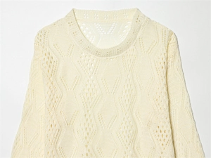 Close-up of cream knit sweater showing diamond hollow-out patterns and textured crochet