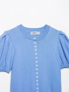 Close-up of blue knit cardigan featuring white buttons and puff sleeve detail