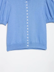 Detail of sky blue knit cardigan with puff sleeves and small white buttons