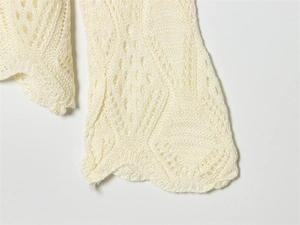 Detailed close-up of diamond hollow-out knit pattern and scalloped hem on cream sweater