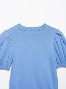 Macro shot of blue knit top featuring elegant puff sleeves and a classic crew neck design