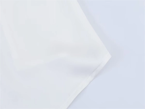 Detaillierte Nahaufnahme der Naht und Satin-Textur am Saum des weißen Oberteils für Damen