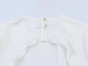 Detail eines weißen Satintops mit Tropfenausschnitt am Rücken und eleganten Perlenknöpfen